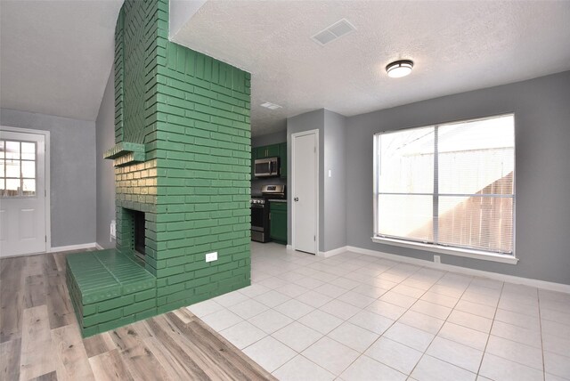 unfurnished living room featuring a textured ceiling, light hardwood / wood-style floors, lofted ceiling, and a fireplace