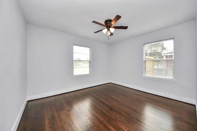 spare room featuring dark hardwood / wood-style floors, ceiling fan, and a wealth of natural light