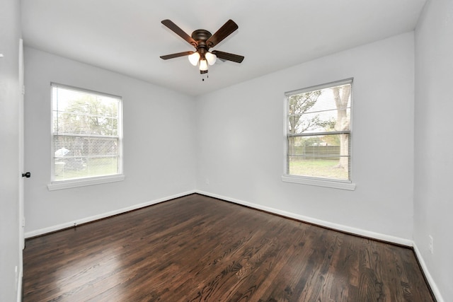 empty room with a wealth of natural light, ceiling fan, and dark wood-type flooring