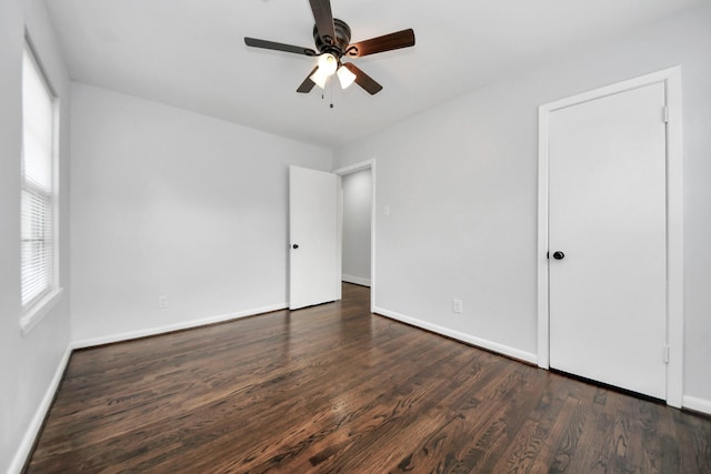 unfurnished room featuring a healthy amount of sunlight, ceiling fan, and dark wood-type flooring