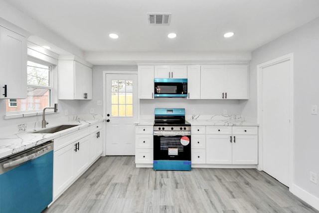 kitchen with light stone countertops, white cabinetry, sink, and stainless steel appliances