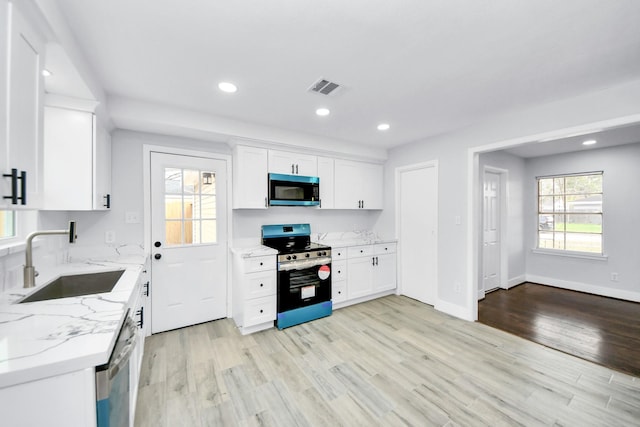 kitchen with light stone countertops, sink, white cabinetry, and stainless steel appliances