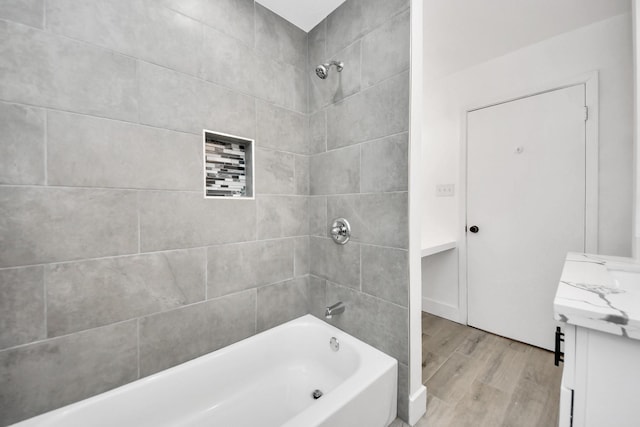 bathroom with hardwood / wood-style floors, vanity, and tiled shower / bath