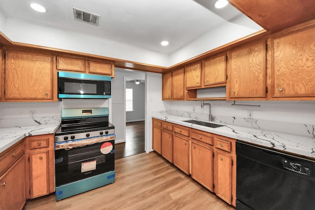 kitchen with sink, light hardwood / wood-style flooring, ceiling fan, light stone countertops, and appliances with stainless steel finishes