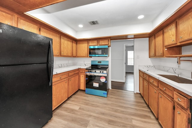 kitchen featuring light wood-type flooring, sink, and appliances with stainless steel finishes