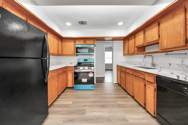 kitchen featuring sink, light hardwood / wood-style flooring, and black appliances