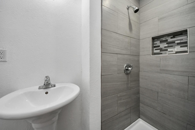 bathroom featuring a tile shower and sink