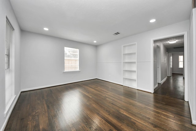 empty room featuring built in shelves and dark wood-type flooring