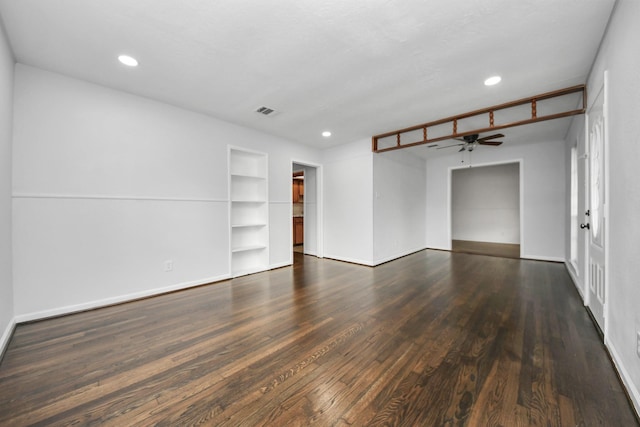 empty room featuring built in shelves and dark wood-type flooring