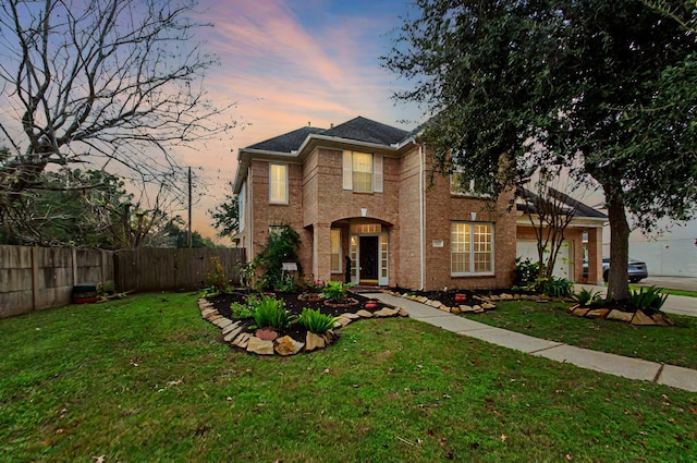 traditional home featuring brick siding, fence, driveway, and a front lawn