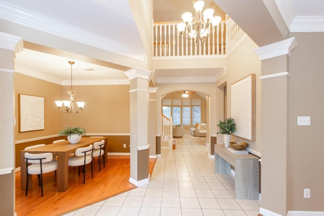 interior space featuring light tile patterned floors, decorative columns, crown molding, and a notable chandelier