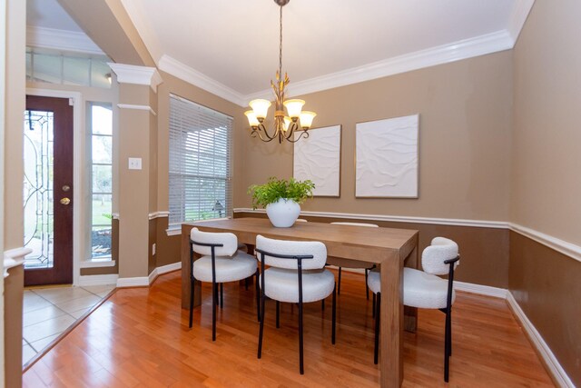 dining space featuring plenty of natural light, crown molding, light hardwood / wood-style flooring, and a chandelier