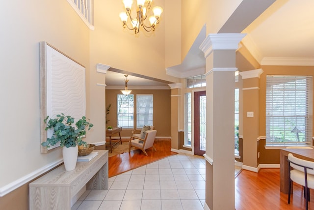 entrance foyer with decorative columns, a wealth of natural light, light hardwood / wood-style flooring, and a chandelier