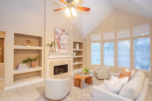 tiled living room with a fireplace, built in shelves, ceiling fan, and lofted ceiling