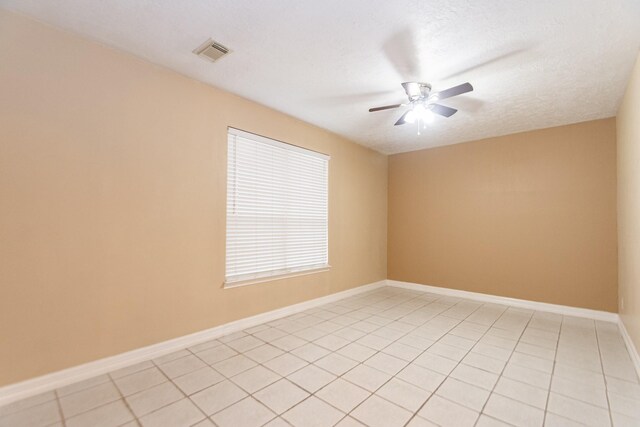 tiled empty room featuring ceiling fan and a textured ceiling