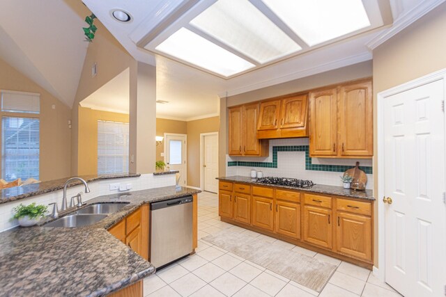 kitchen with appliances with stainless steel finishes, tasteful backsplash, sink, dark stone countertops, and light tile patterned flooring