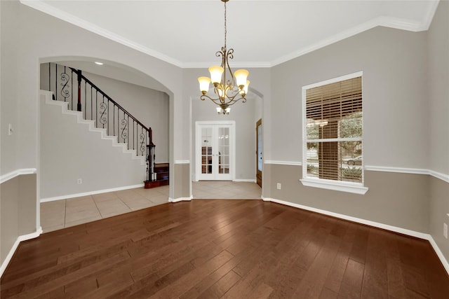 interior space with french doors, hardwood / wood-style flooring, ornamental molding, and a notable chandelier