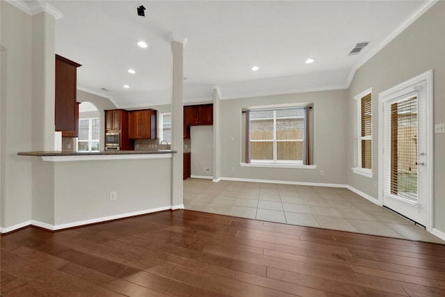 kitchen with light wood-type flooring, kitchen peninsula, and ornamental molding