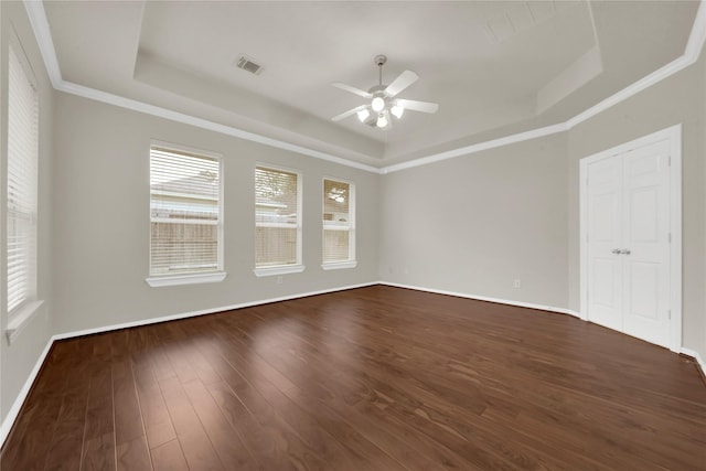 empty room with dark hardwood / wood-style floors, a raised ceiling, ceiling fan, and ornamental molding