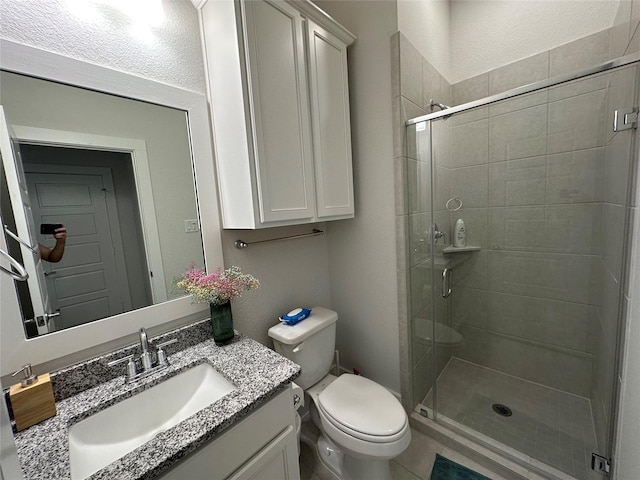 bathroom with toilet, vanity, and a shower with shower door