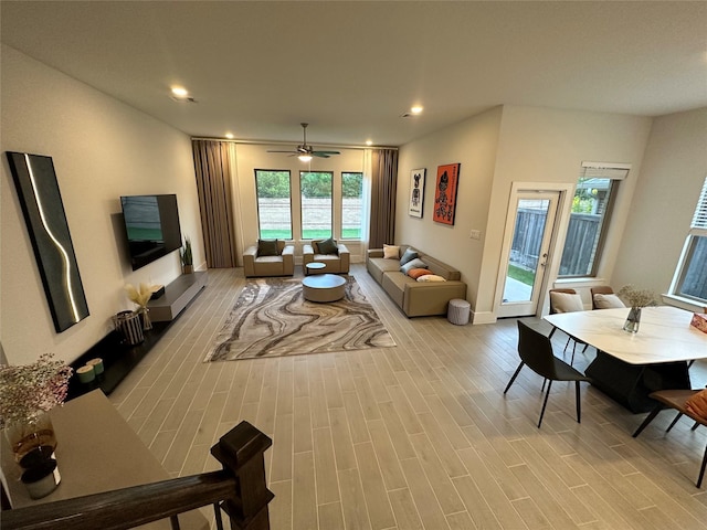 living room featuring ceiling fan, light hardwood / wood-style flooring, and a wealth of natural light