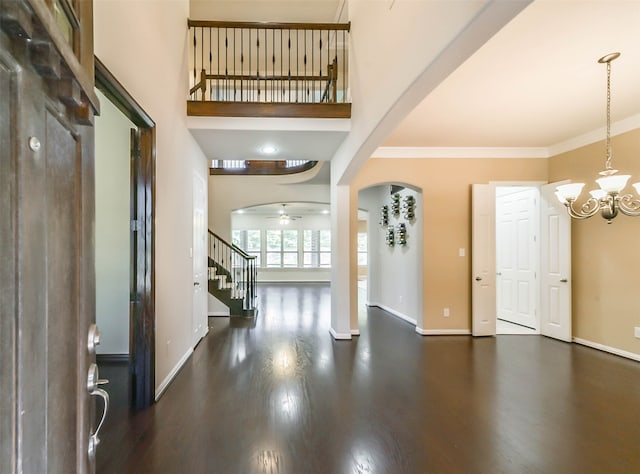 entrance foyer with ceiling fan with notable chandelier, dark hardwood / wood-style flooring, and ornamental molding