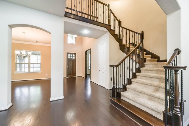 foyer featuring a notable chandelier, ornamental molding, and dark wood-type flooring