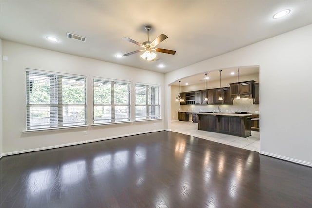 unfurnished living room with ceiling fan, sink, and light hardwood / wood-style flooring