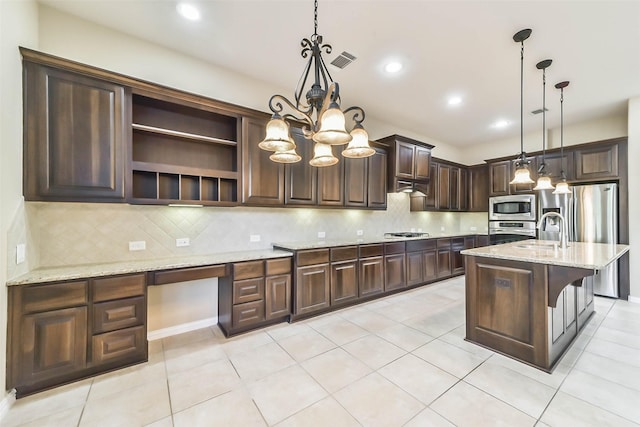 kitchen with light stone countertops, pendant lighting, a kitchen island with sink, dark brown cabinets, and appliances with stainless steel finishes