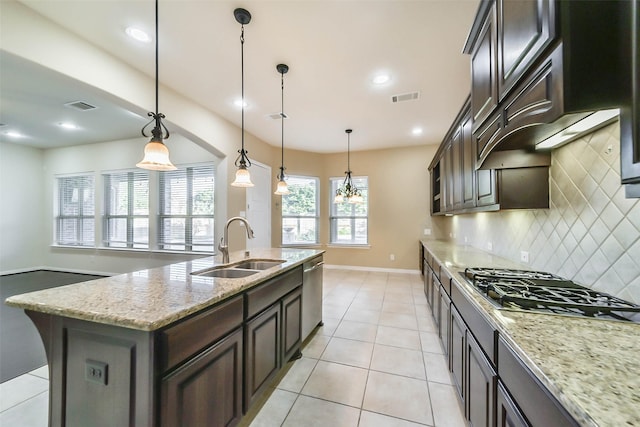 kitchen with a center island with sink, sink, hanging light fixtures, light stone countertops, and appliances with stainless steel finishes