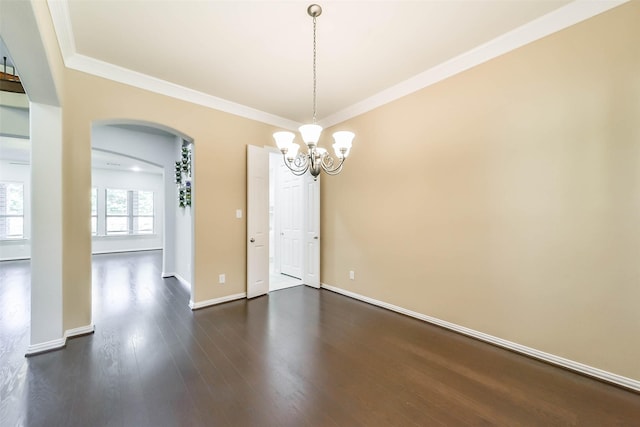 empty room with dark hardwood / wood-style floors, crown molding, and a chandelier