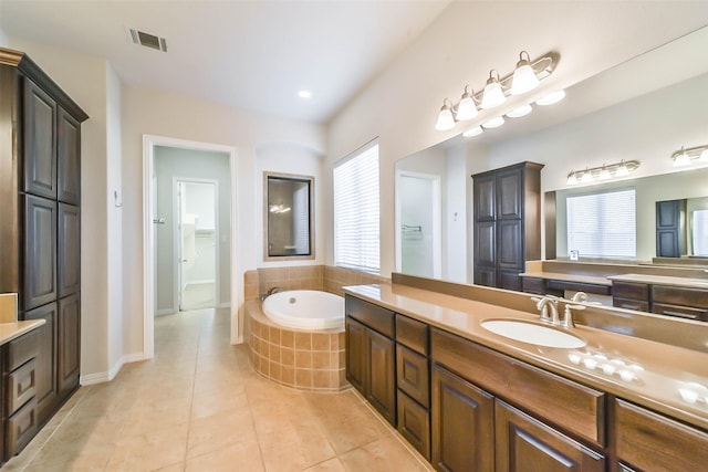 bathroom featuring tile patterned flooring, vanity, and tiled tub