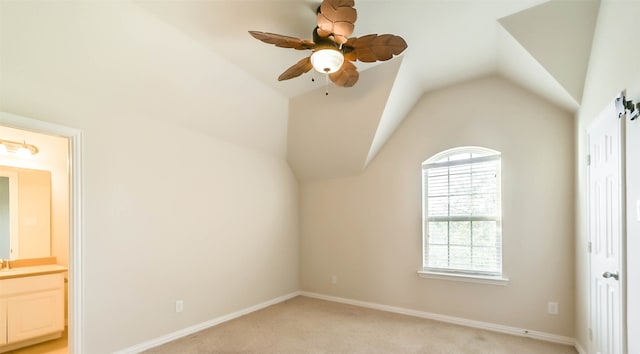 unfurnished bedroom with lofted ceiling, light carpet, ensuite bathroom, sink, and ceiling fan