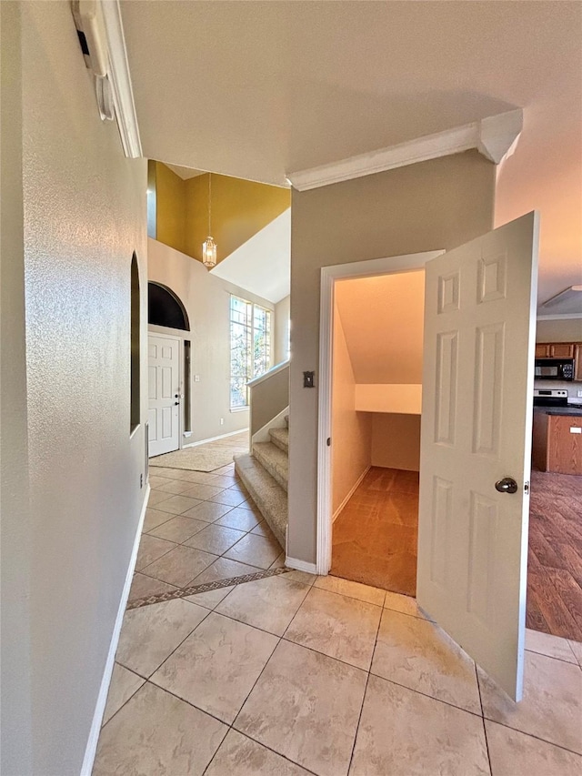 hall with a notable chandelier, light tile patterned floors, and ornamental molding