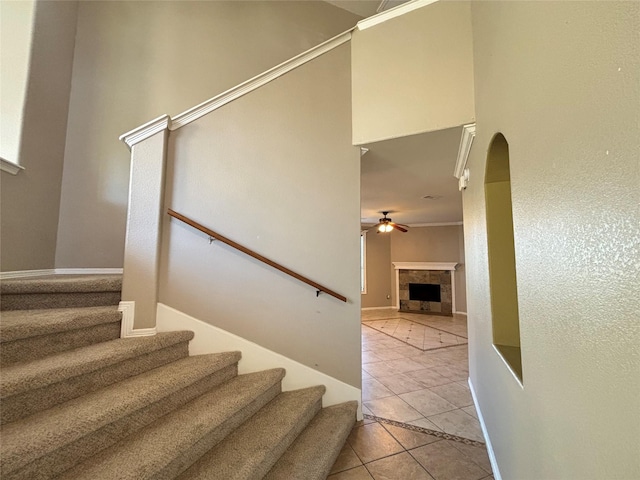 stairway featuring a tile fireplace, tile patterned flooring, and ceiling fan