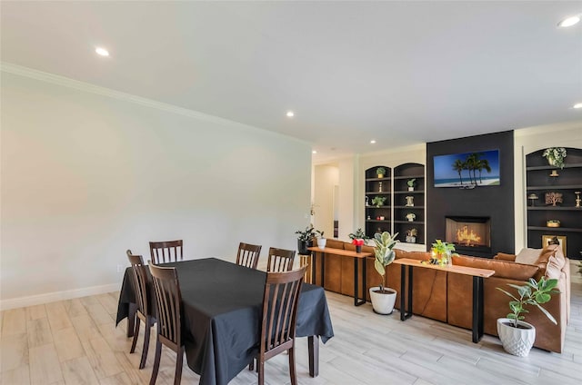 dining space with built in features, crown molding, and light hardwood / wood-style flooring