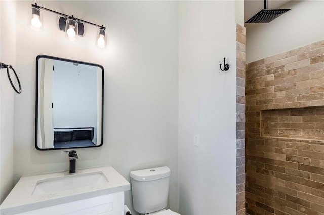 bathroom with vanity, toilet, walk in shower, and brick wall