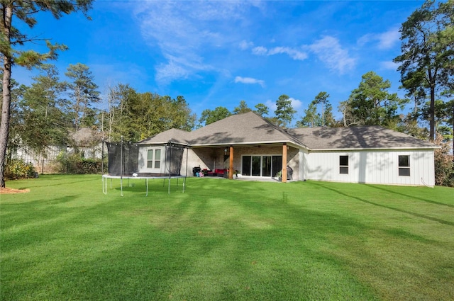 rear view of house with a yard and a trampoline