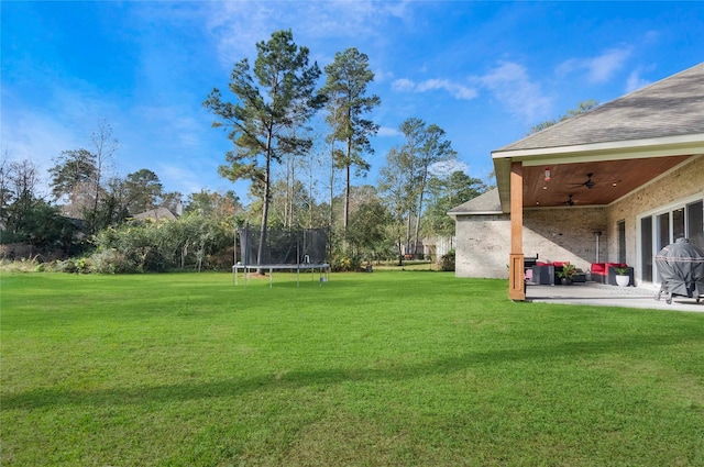 view of yard with ceiling fan, a trampoline, and a patio