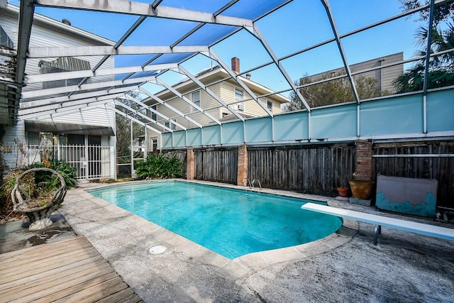 view of pool featuring glass enclosure and a diving board