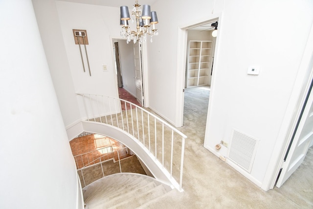 staircase featuring ceiling fan with notable chandelier and carpet floors