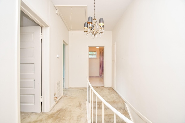 hallway with carpet and a notable chandelier