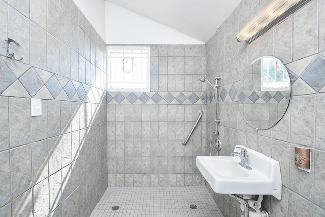 bathroom with a tile shower, lofted ceiling, and sink