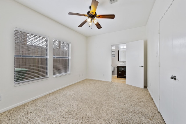 unfurnished bedroom featuring ceiling fan, light colored carpet, and ensuite bathroom