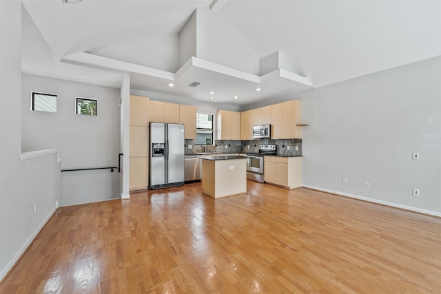 kitchen featuring appliances with stainless steel finishes, backsplash, light brown cabinets, high vaulted ceiling, and a kitchen island