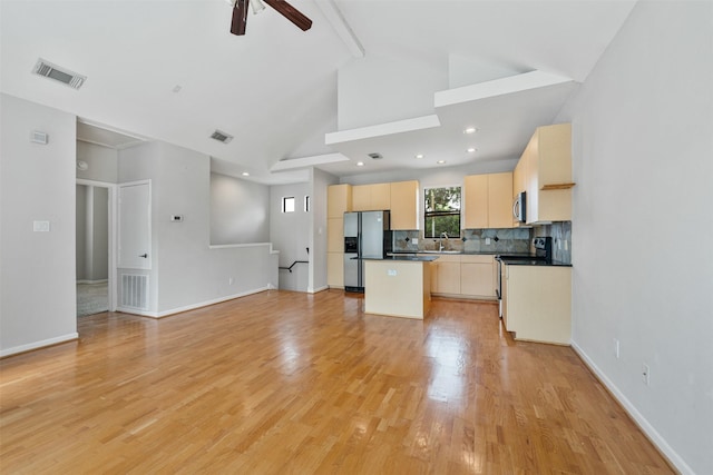 kitchen featuring ceiling fan, sink, stainless steel appliances, backsplash, and a kitchen island