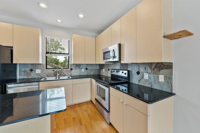 kitchen with decorative backsplash, appliances with stainless steel finishes, sink, light hardwood / wood-style flooring, and cream cabinetry