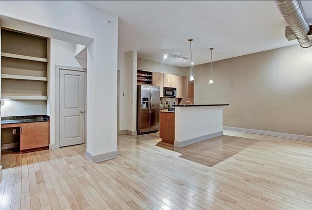 kitchen featuring stainless steel refrigerator with ice dispenser, light hardwood / wood-style flooring, built in shelves, decorative backsplash, and decorative light fixtures