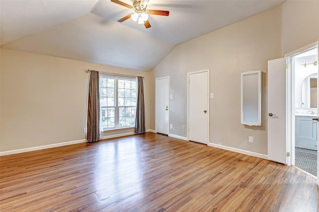 unfurnished bedroom featuring ceiling fan, light hardwood / wood-style flooring, ensuite bathroom, and vaulted ceiling