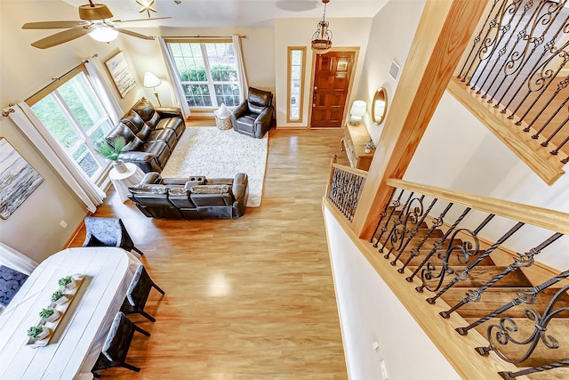 living room featuring ceiling fan, a high ceiling, and hardwood / wood-style flooring